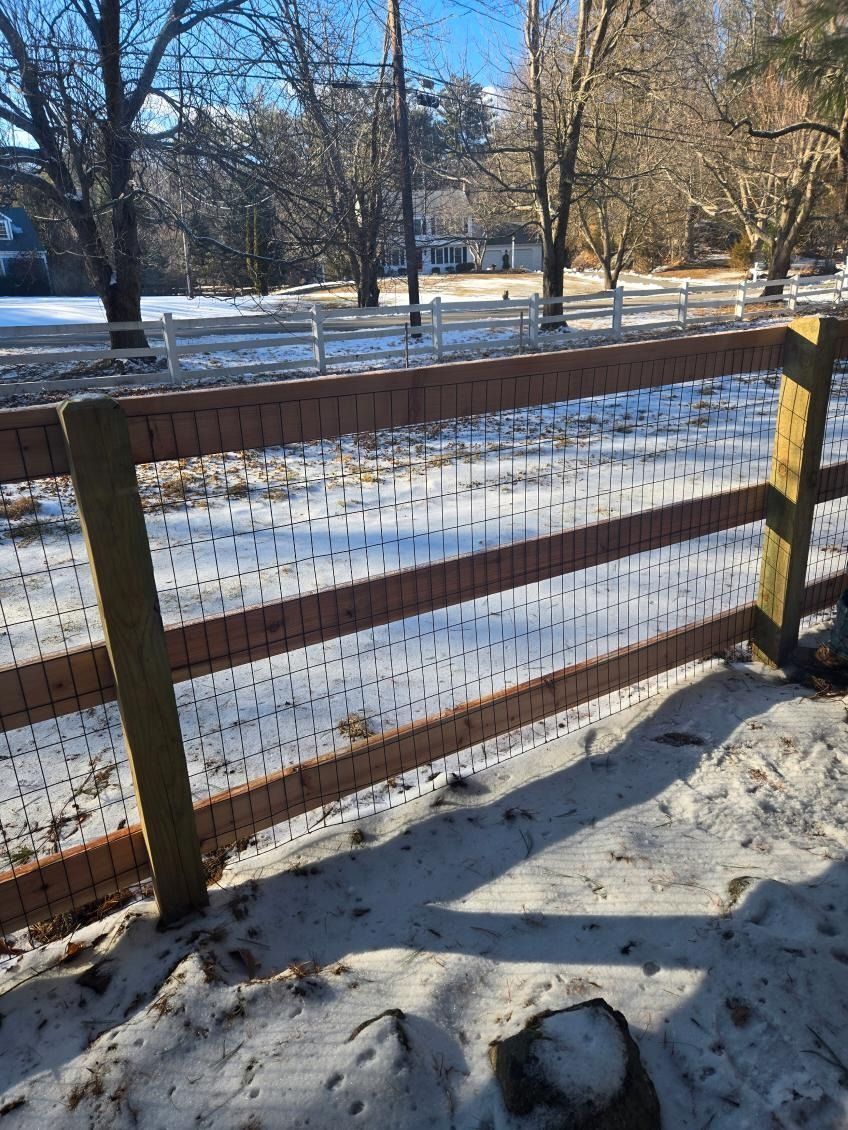 Snowy park seen through a wooden fence on a sunny winter day