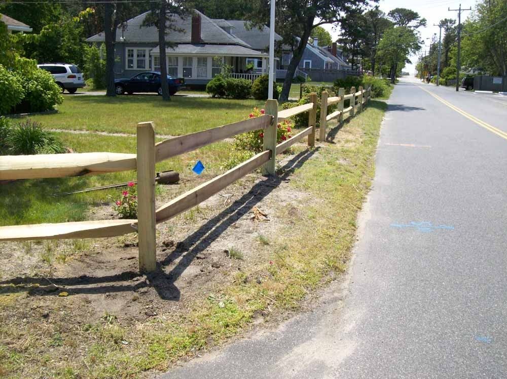 Wooden fence along a roadside beside houses on a sunny day
