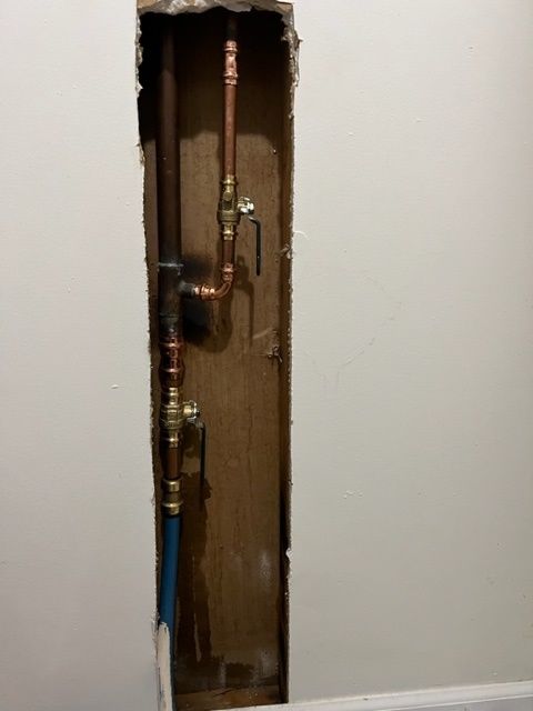 A hole in a wall with copper pipes coming out of it