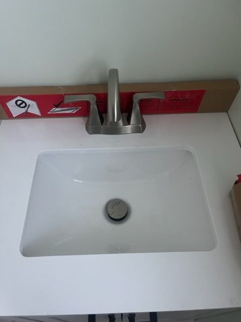 A white bathroom sink with a stainless steel faucet