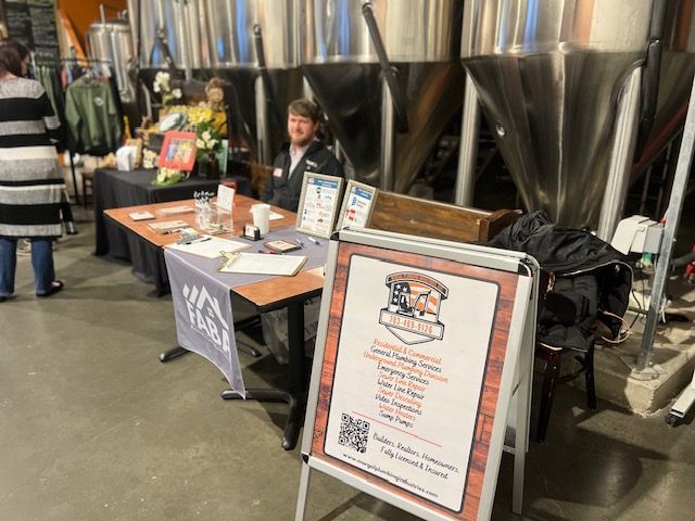 A man is sitting at a table with a sign in front of him.