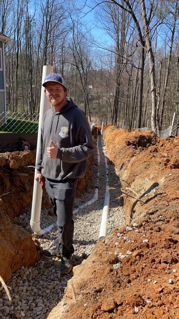 A man is standing in a pile of dirt holding a pipe.