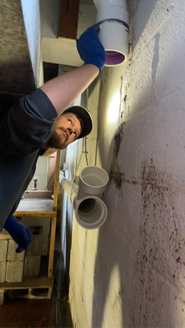 A man is working on a pipe in a basement.