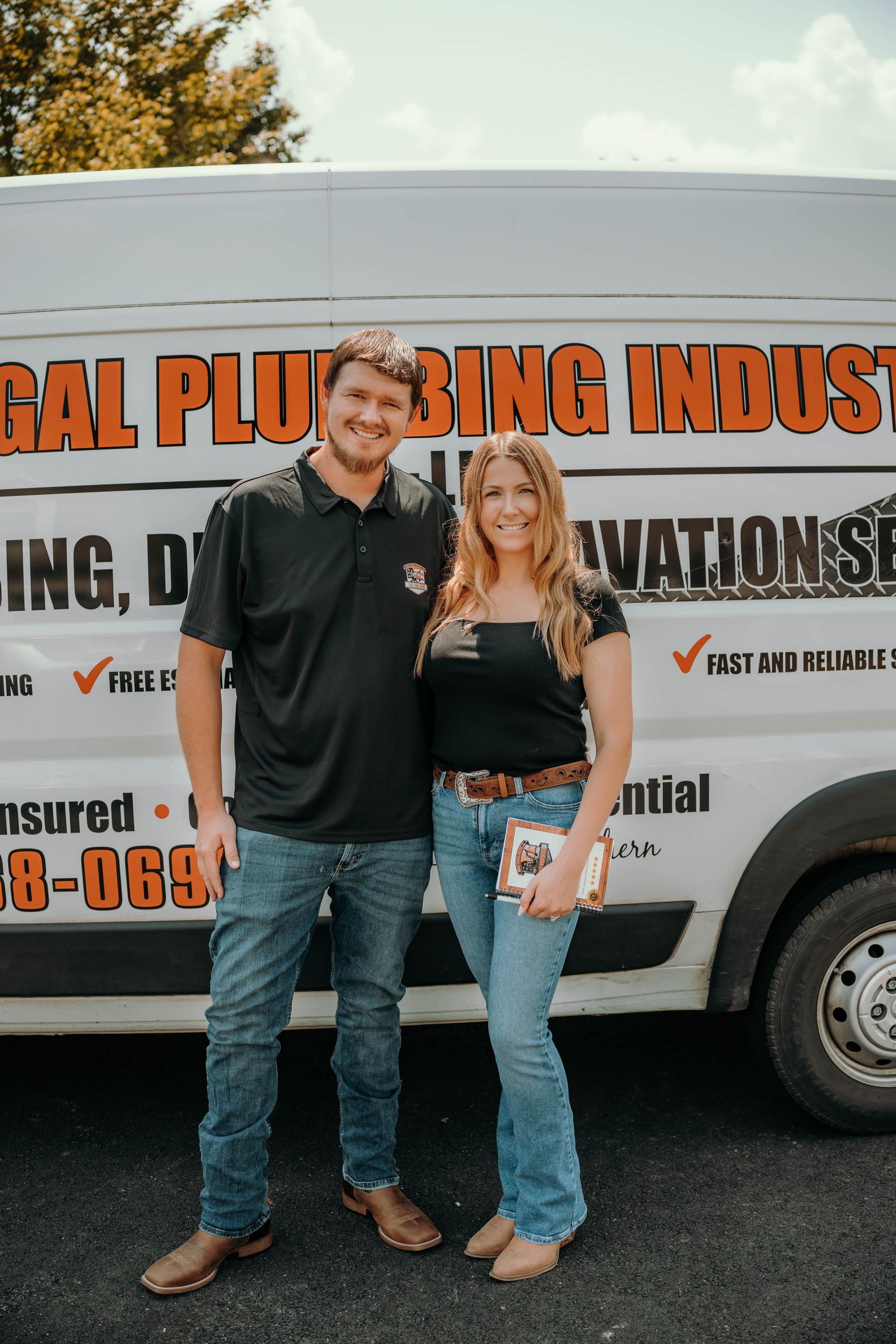 Two people standing next to a white van with plumbing company logos.