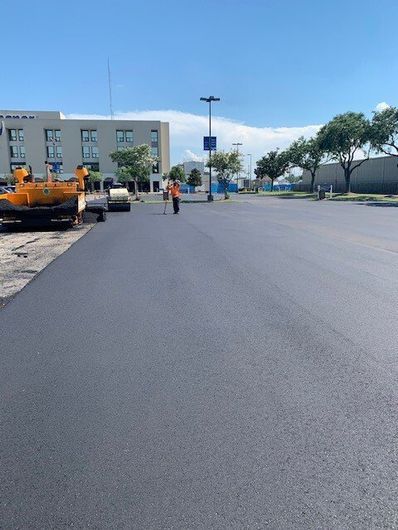 A road is being paved in a parking lot in front of a building.
