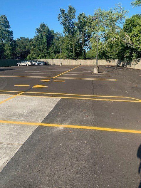 A parking lot with yellow lines and trees in the background