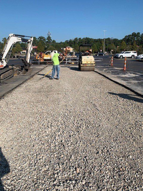 A man is standing on a gravel road next to a bulldozer.