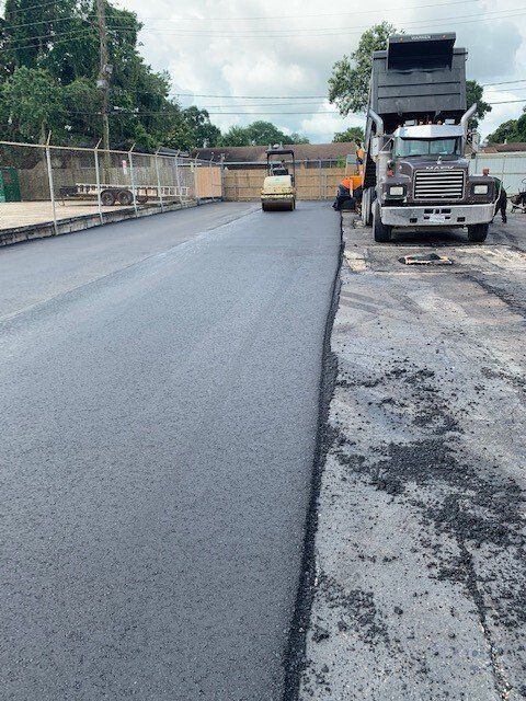 A dump truck is being loaded with asphalt on a road