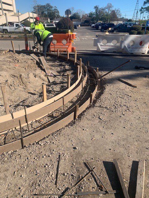 A man is working on a concrete curb in a parking lot