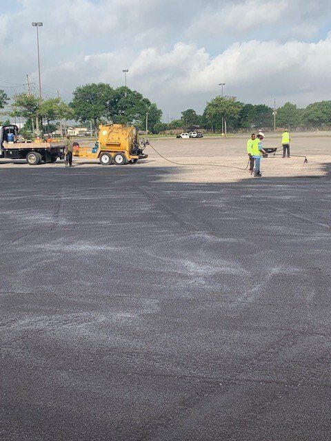 A group of construction workers are working on a parking lot.