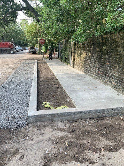 A concrete walkway is being built next to a brick wall.