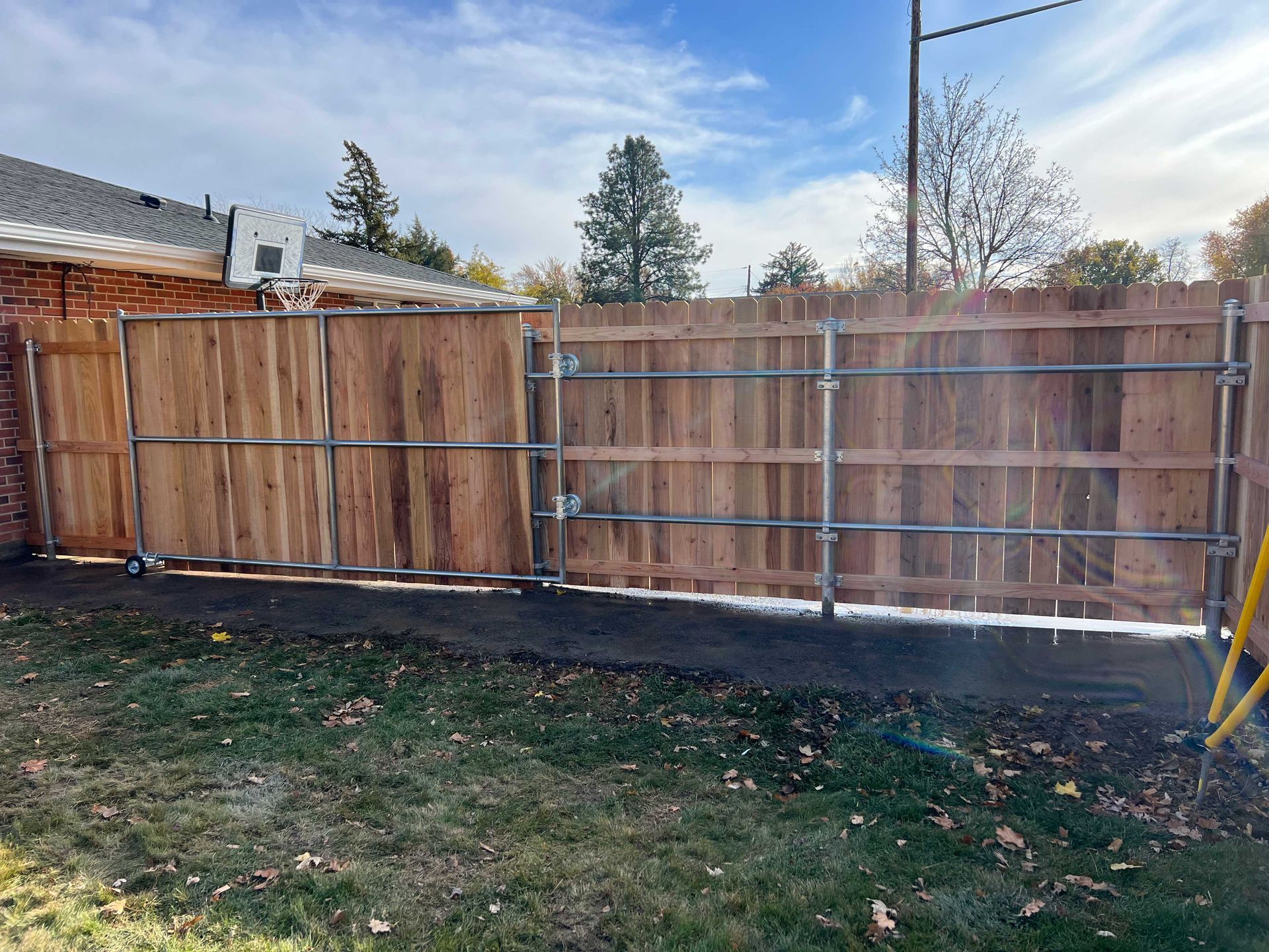Wooden fence with metal frame, in backyard, blue sky.