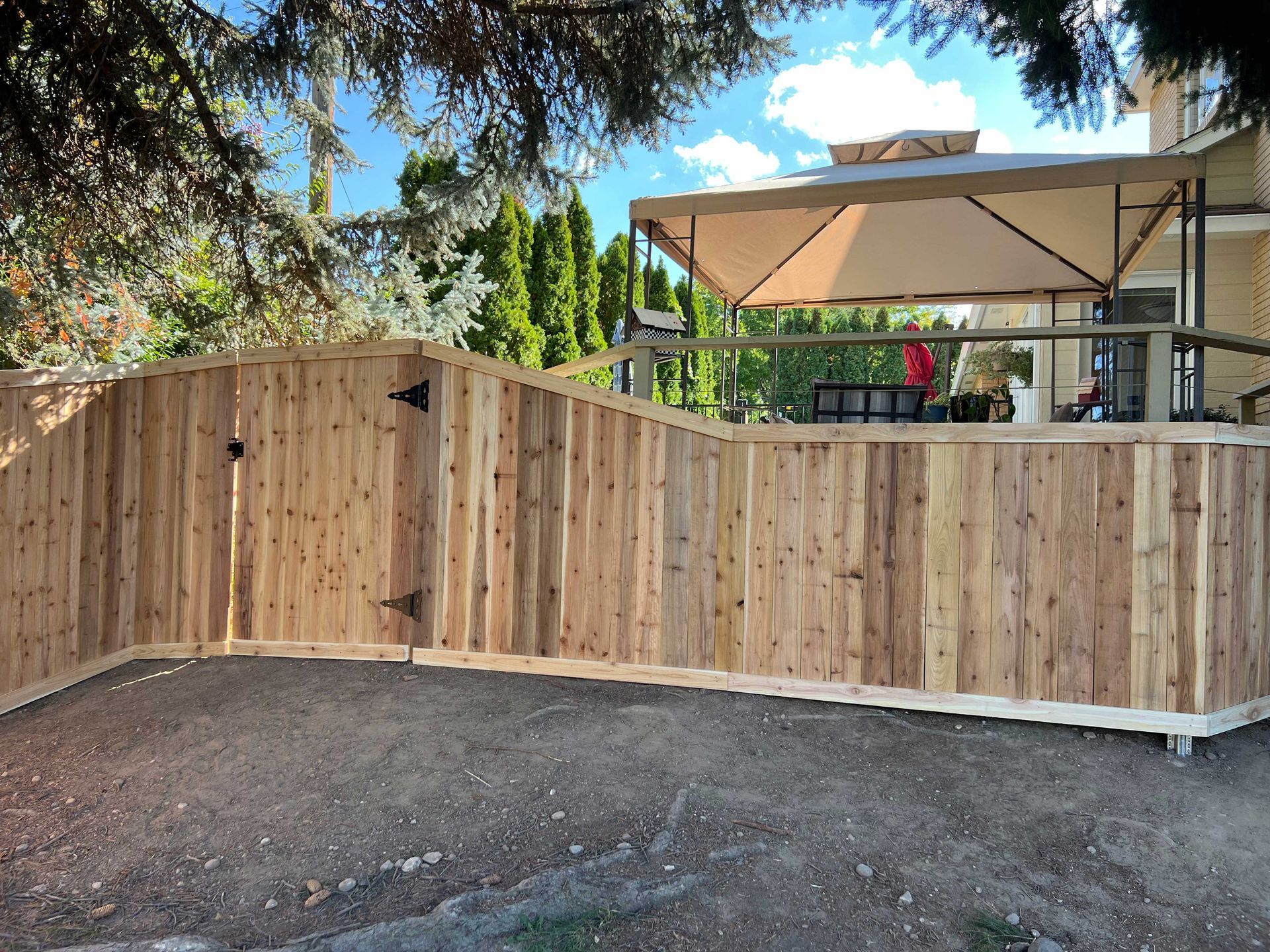 Wooden fence surrounding a backyard deck with a beige canopy.