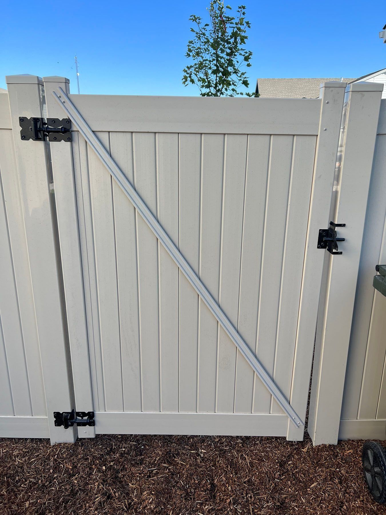 White vinyl gate with black hardware; diagonal support beam.