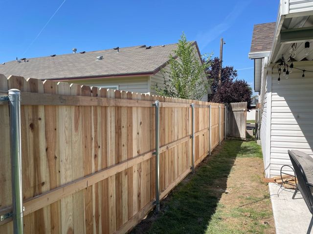 Wooden privacy fence along a house, sunny outdoor setting.