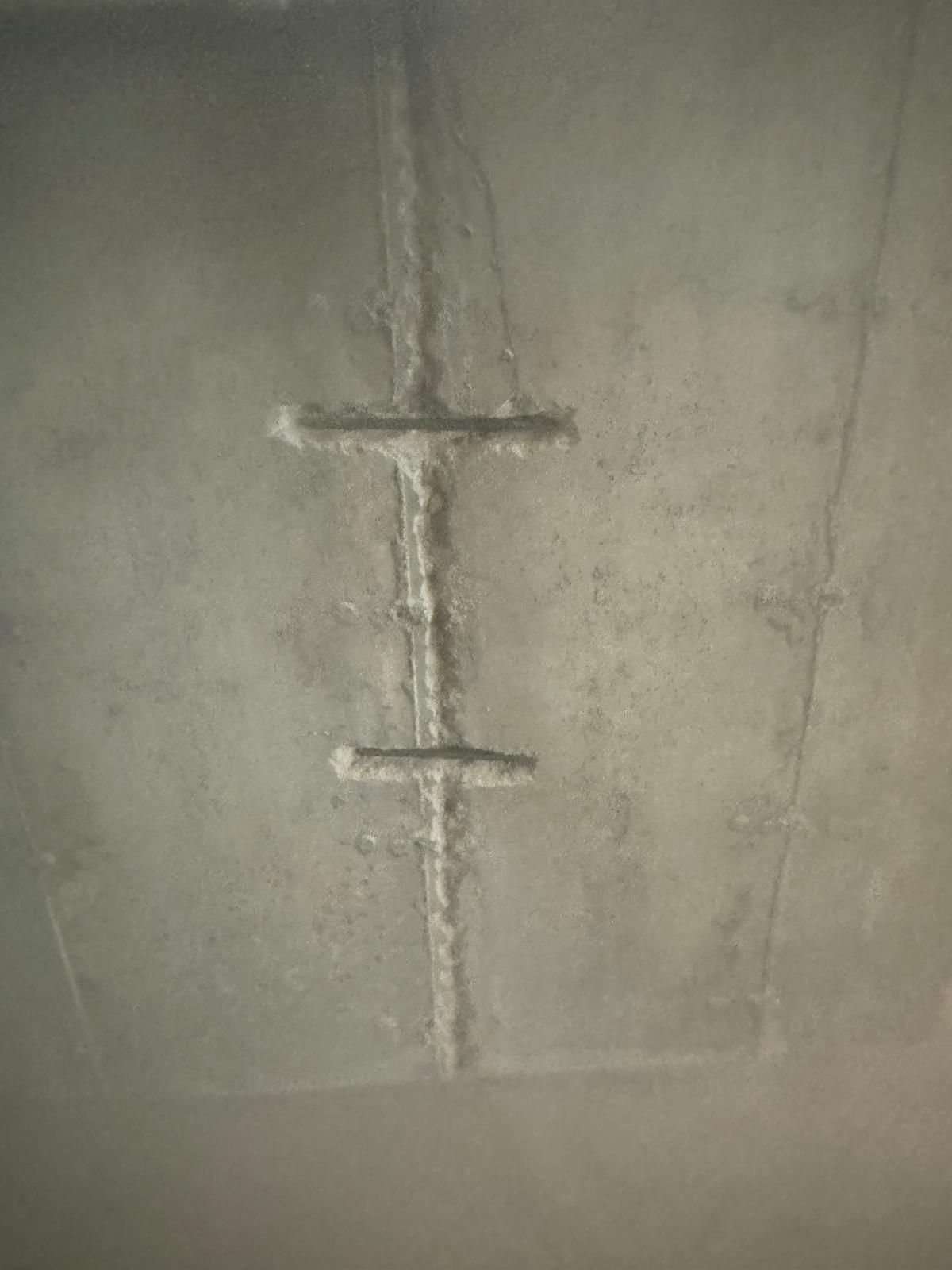 Concrete wall with vertical seam and two horizontal metal brackets.