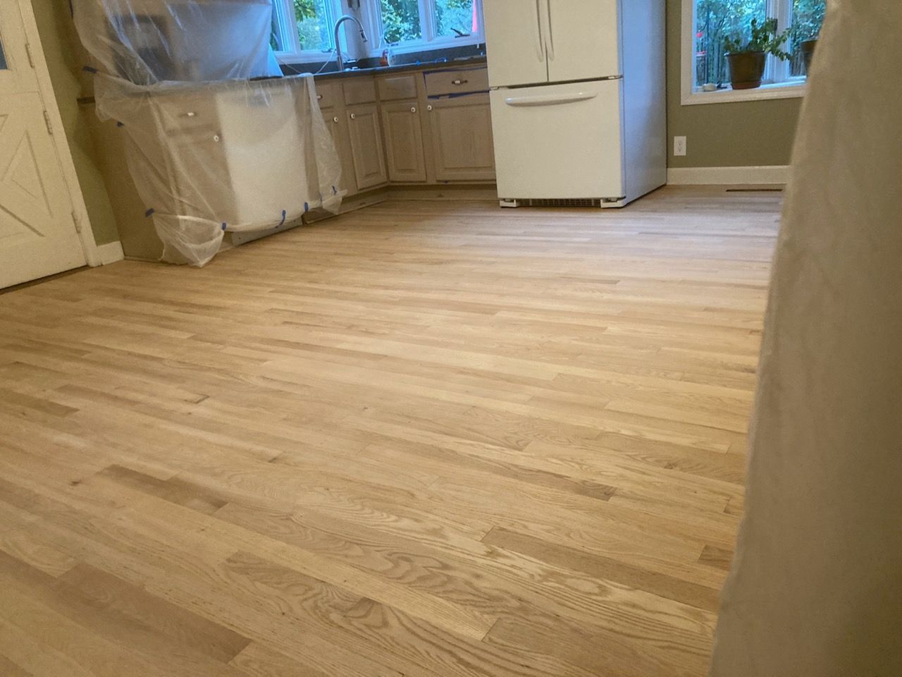 A kitchen with hardwood floors and a refrigerator.