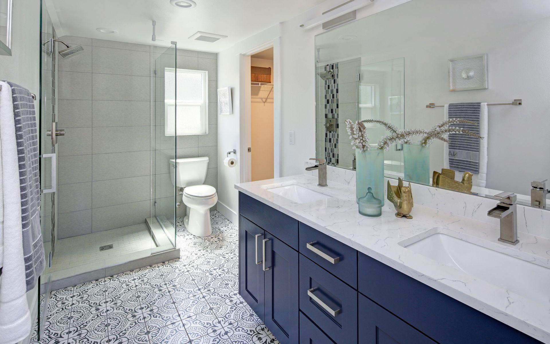 Modern bathroom with blue vanity, white countertop, and glass shower.