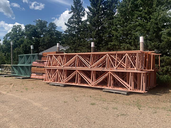 a bunch of wooden beams are stacked on top of each other in a dirt field .