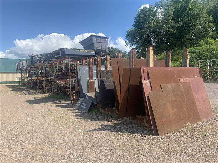 a bunch of metal pieces are stacked on top of each other in a yard .
