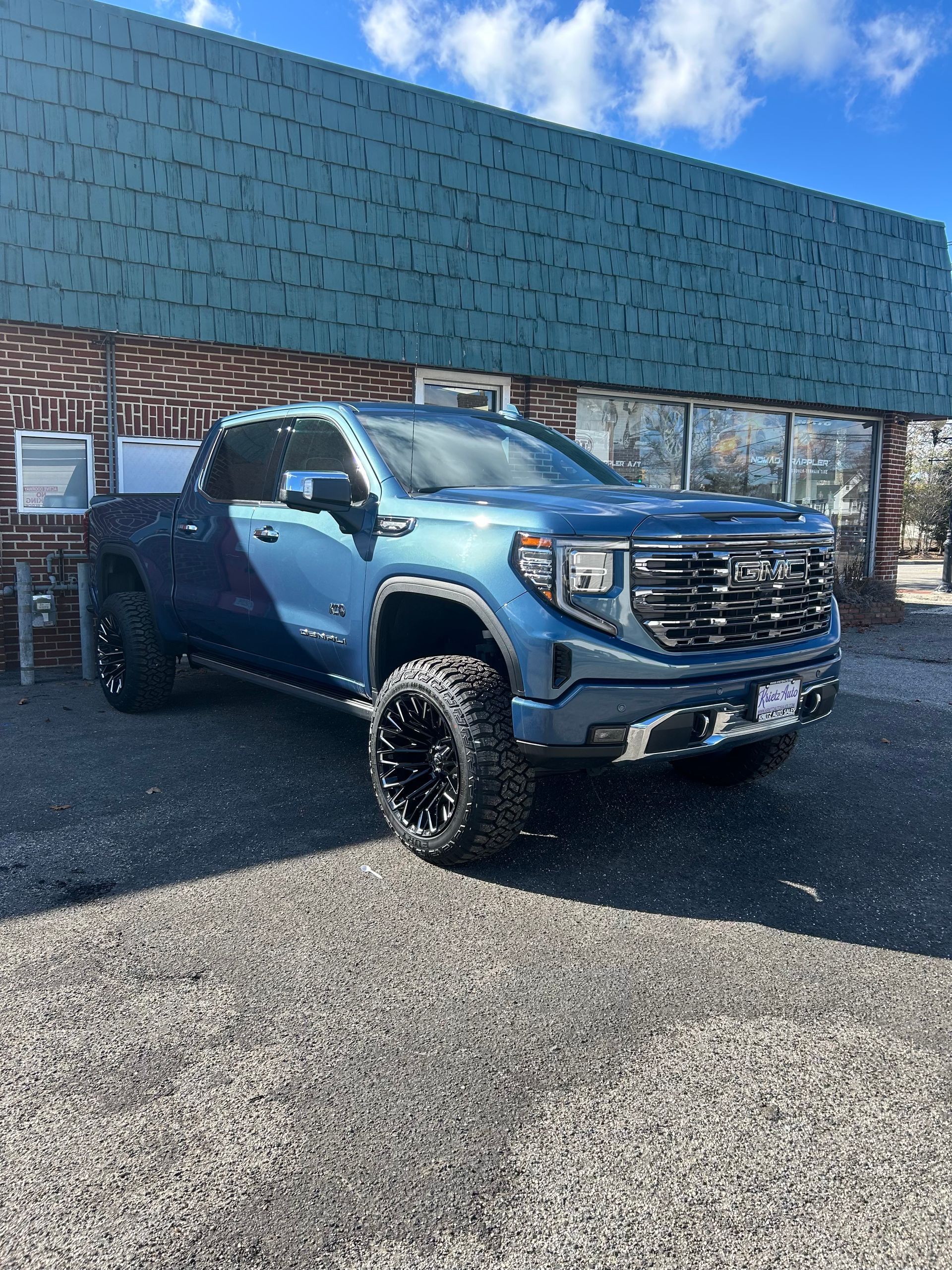 A blue truck is parked in front of a building.