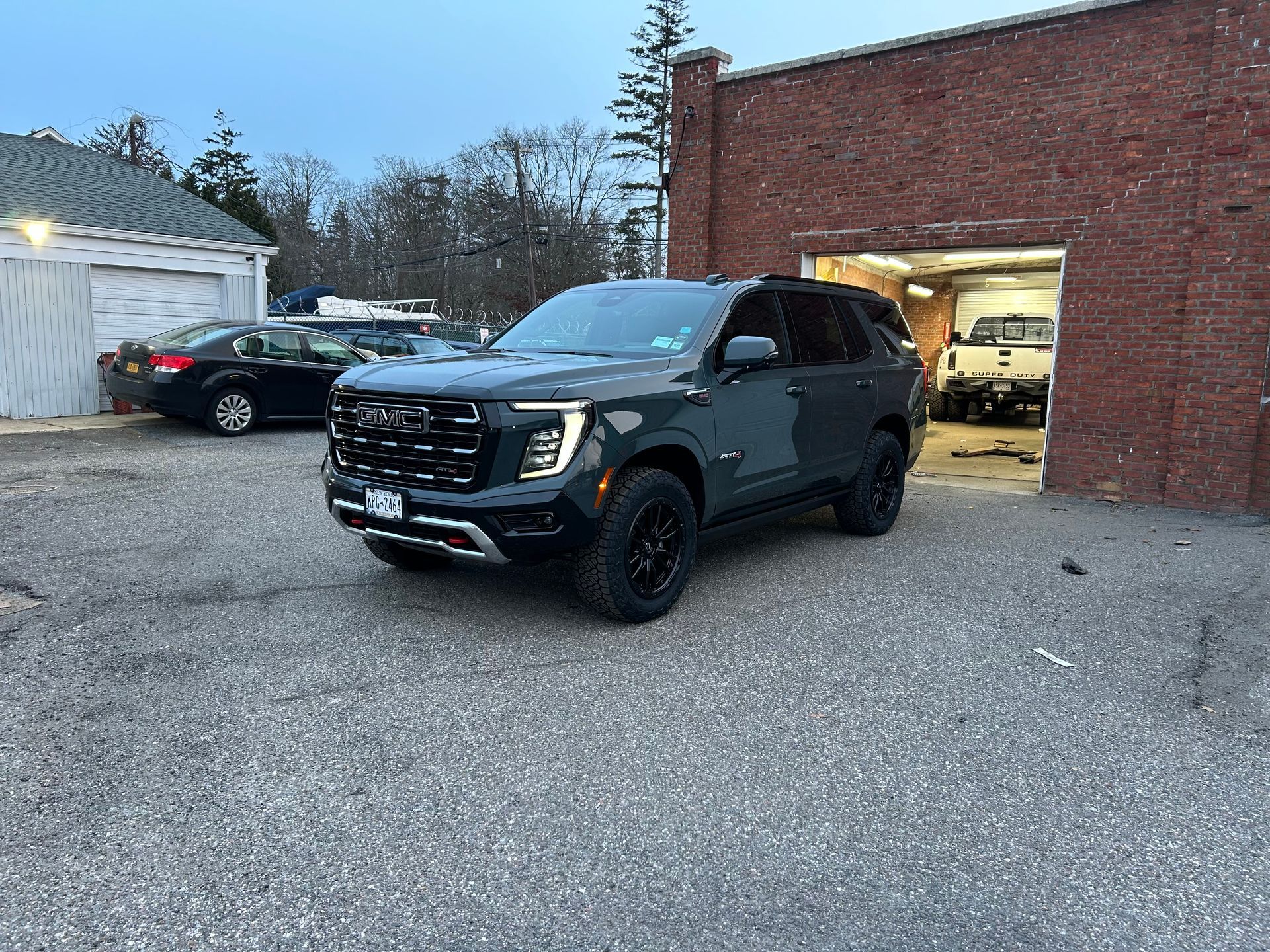 A black suv is parked in a parking lot in front of a brick building.