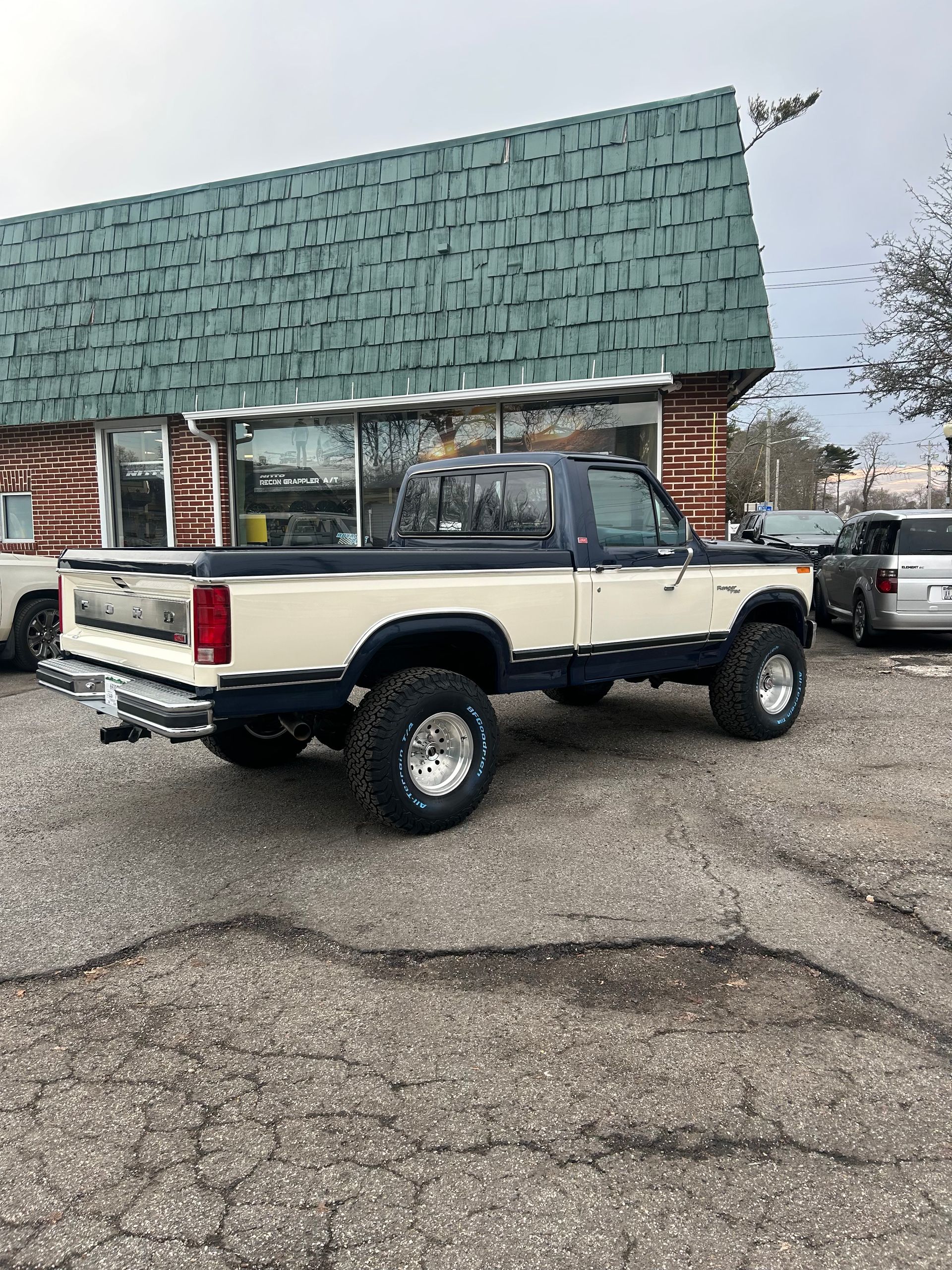 A white truck is parked in front of a building with a green roof.