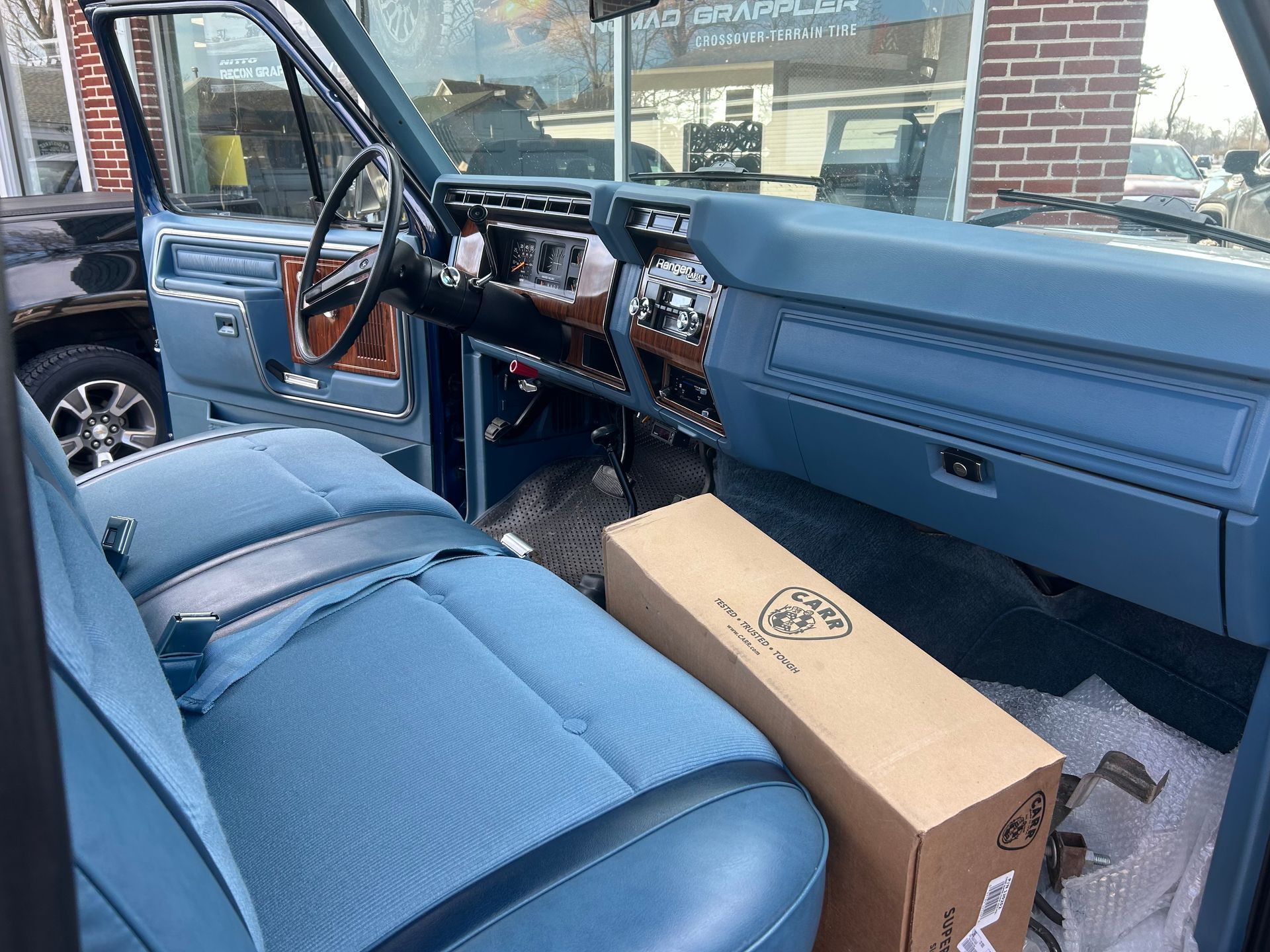 The interior of a blue truck with a box in the back seat.