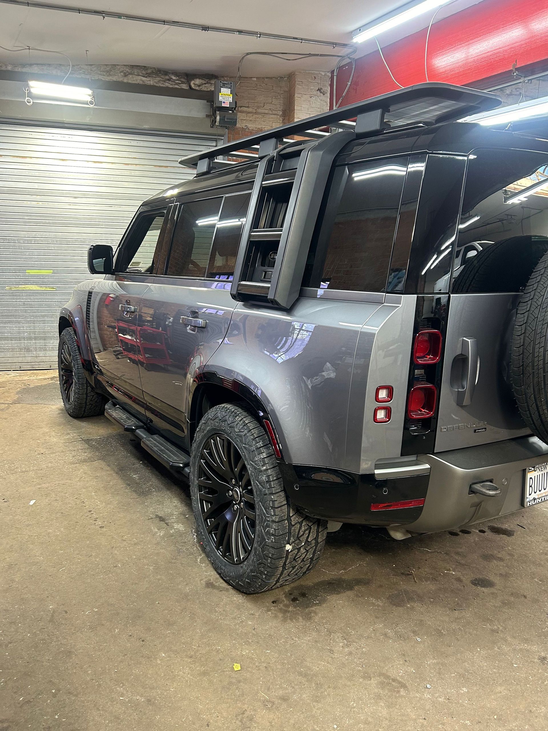 Back-quarter view of a gray Land Rover Defender in a garage
