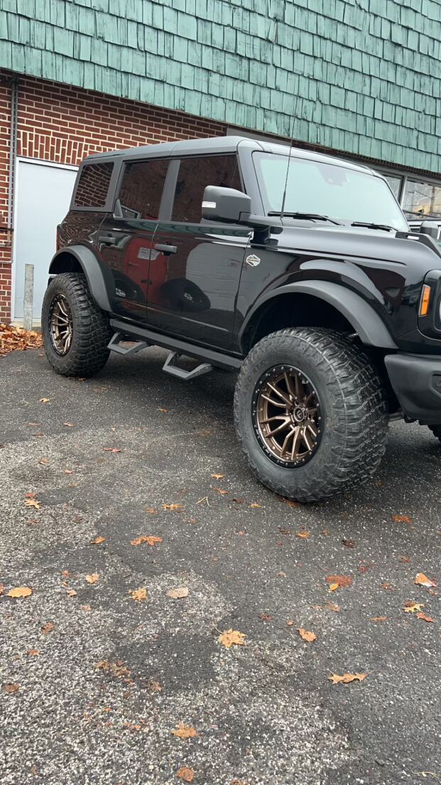 A black Ford Bronco is parked in front of a brick building