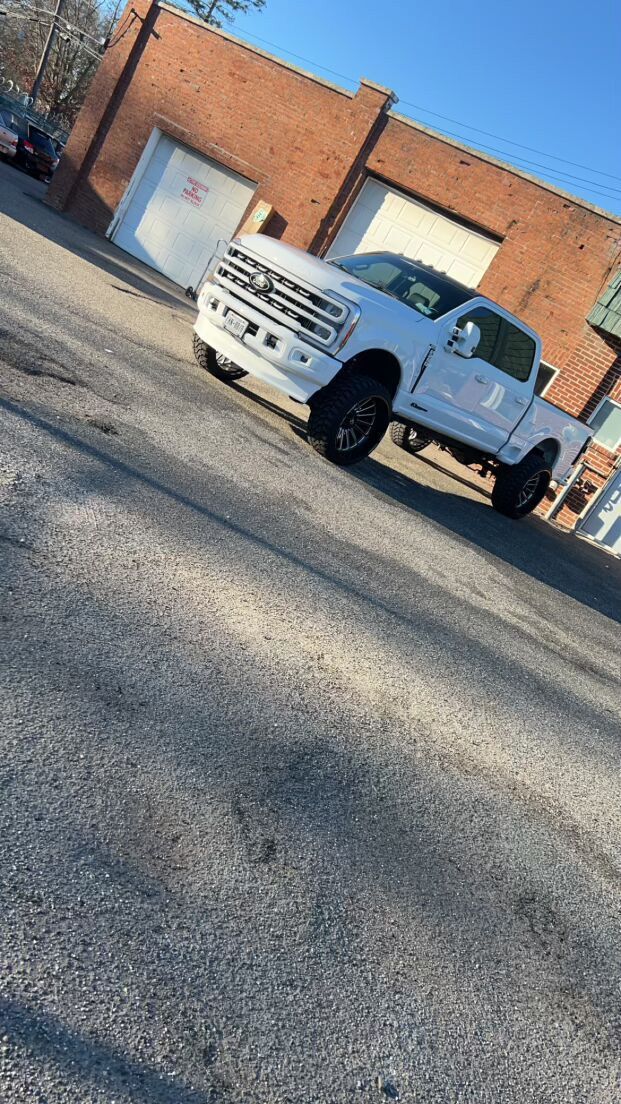 A white truck is parked on the side of the road in front of a brick building