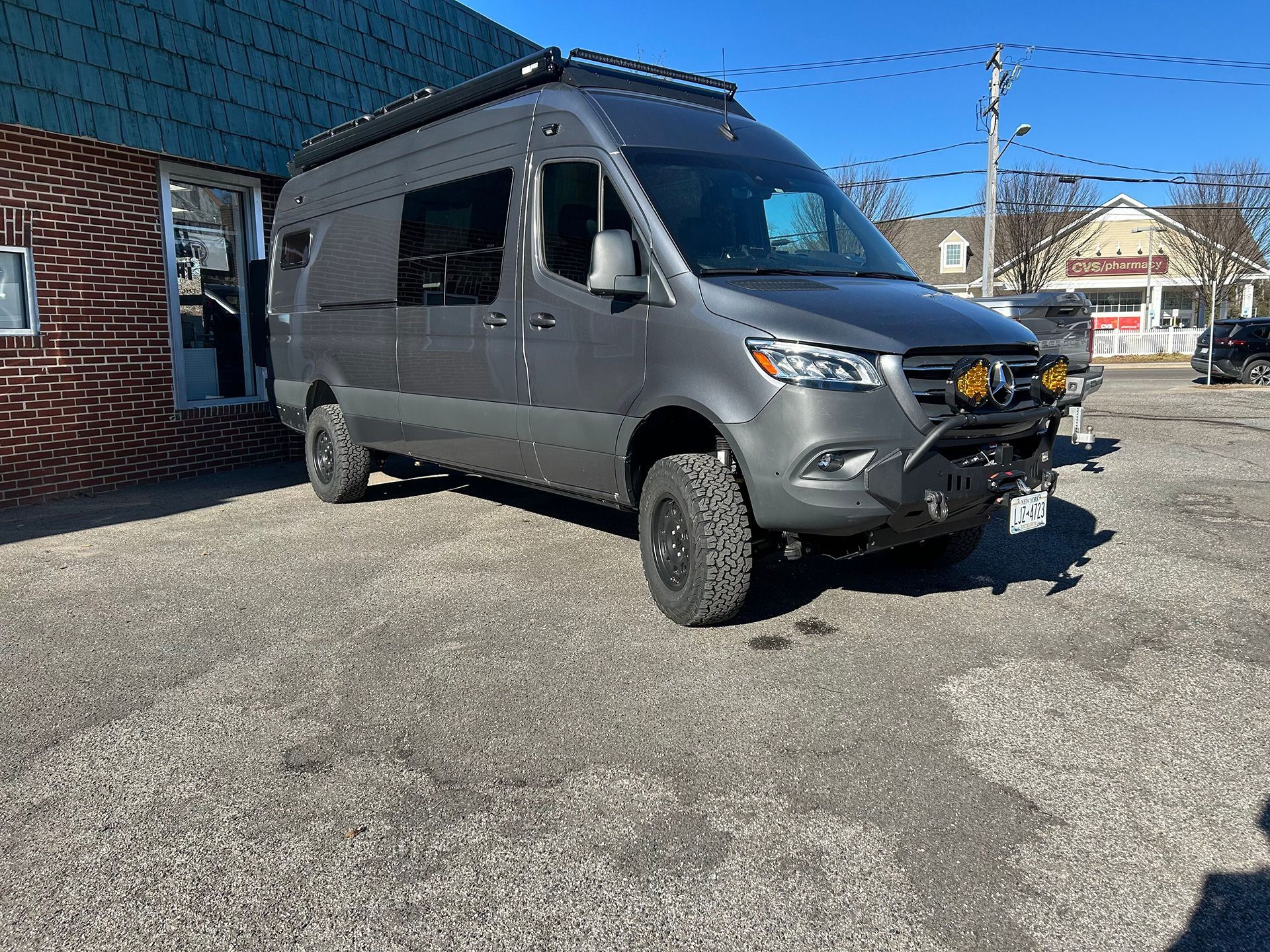 A gray van is parked in front of a brick building