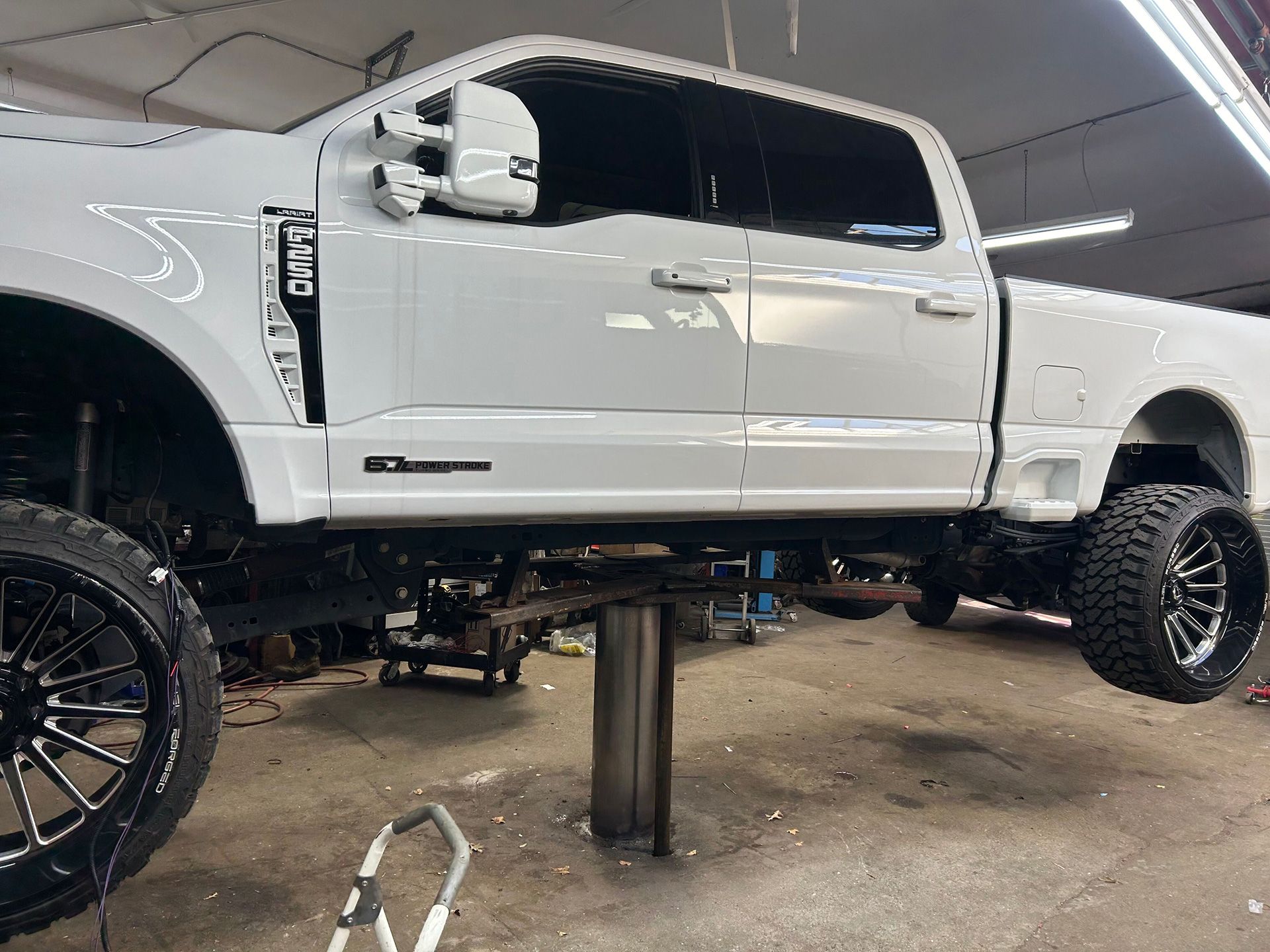 A white truck is sitting on a lift in a garage
