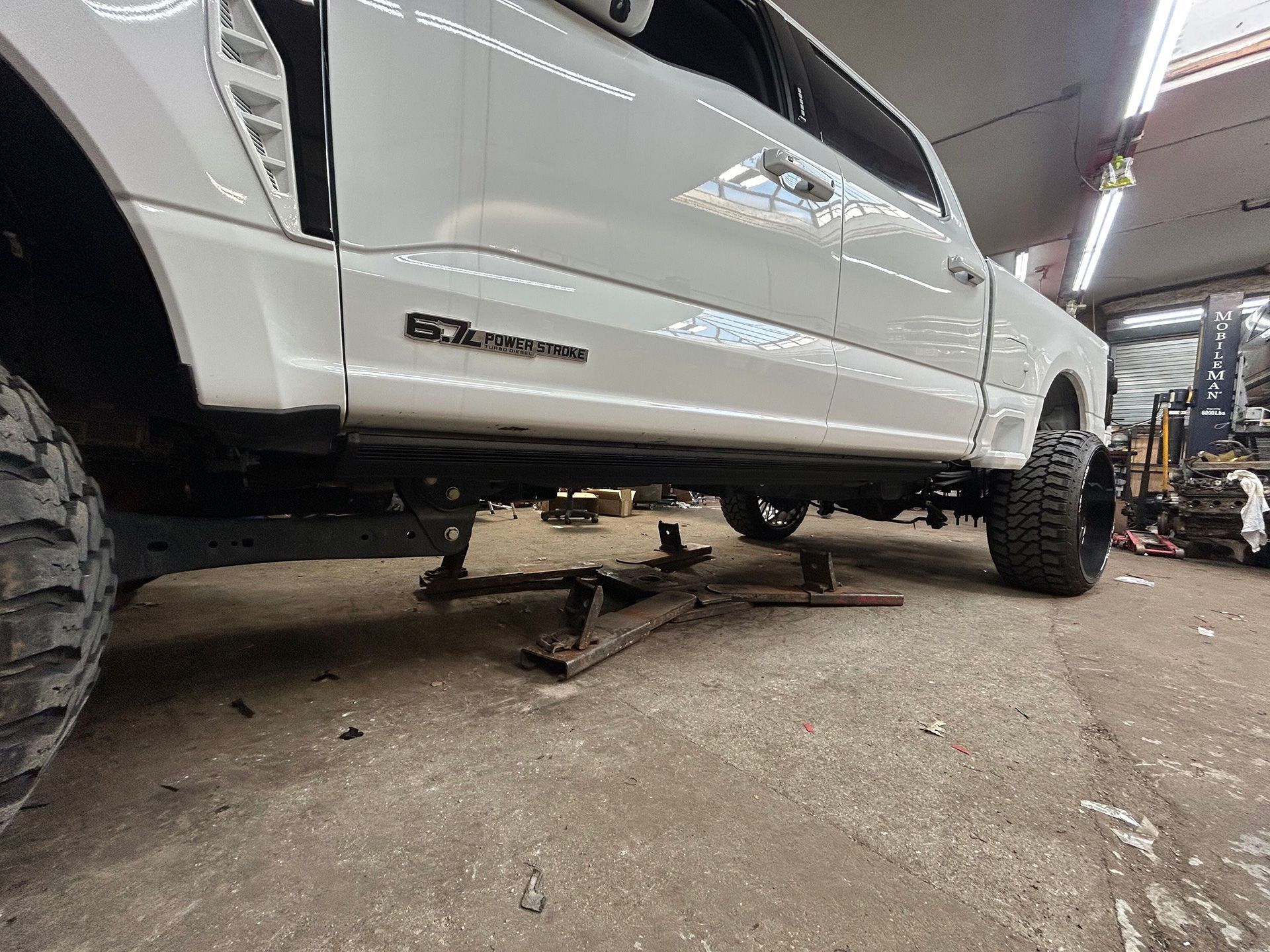 A white truck is sitting on a jack in a garage