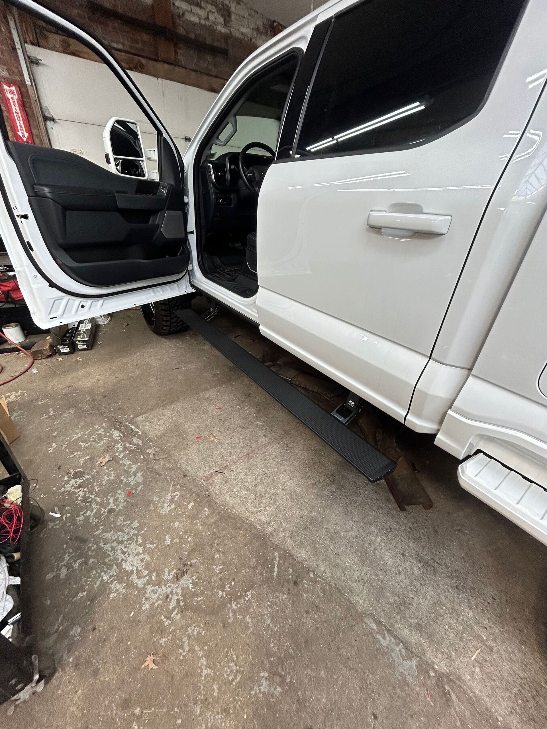 A white truck is parked in a garage with the door open