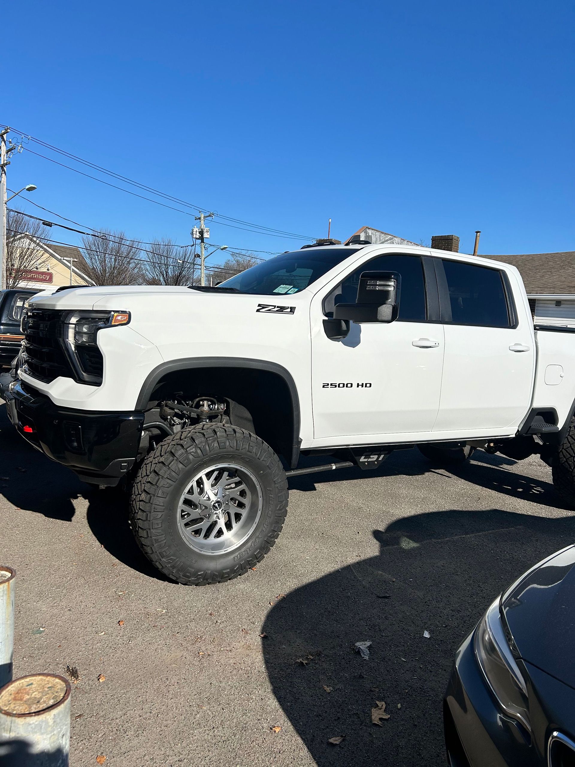 A white truck in a parking lot next to a car