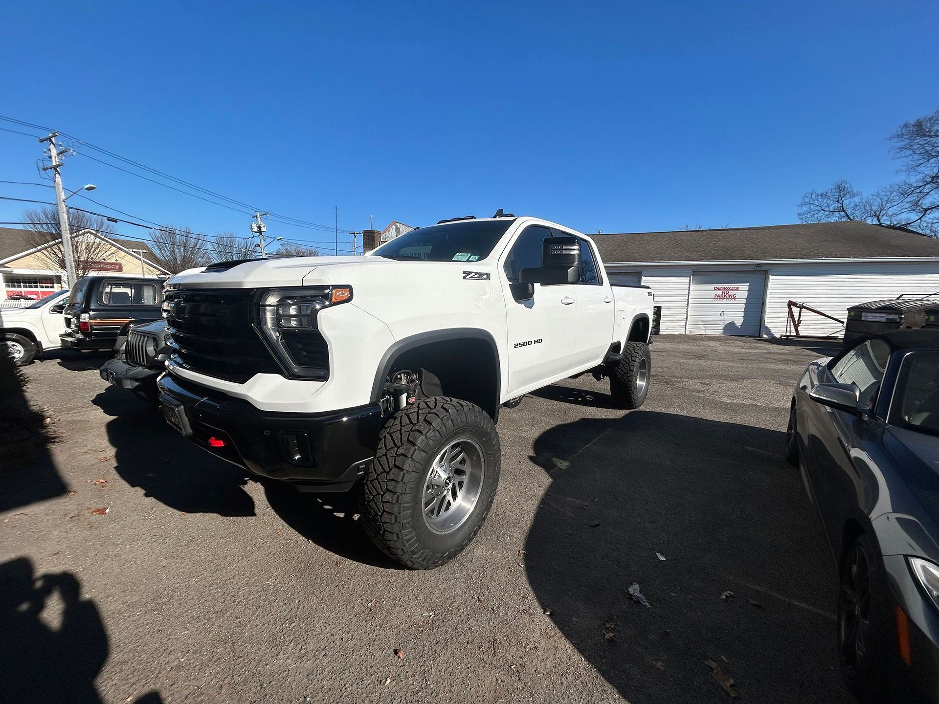 A white truck in a gravel lot in front of a building