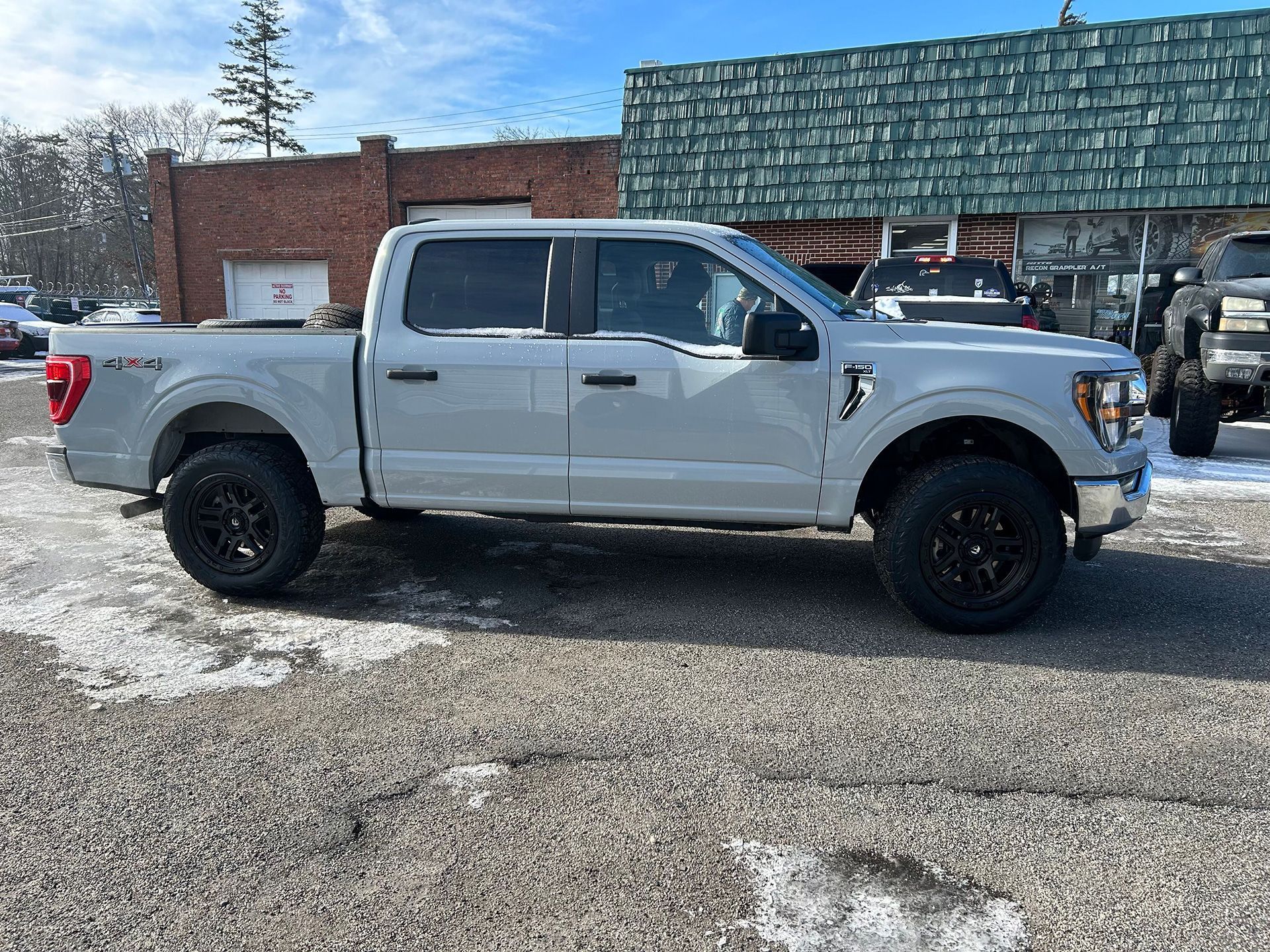 A white pickup truck is parked in front of a brick building