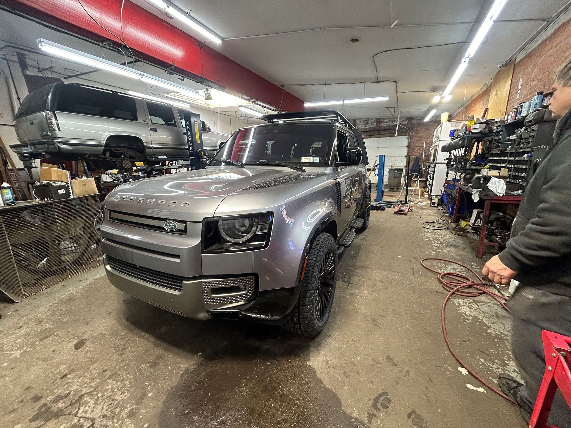 A gray Land Rover Defender is parked in a customization shop
