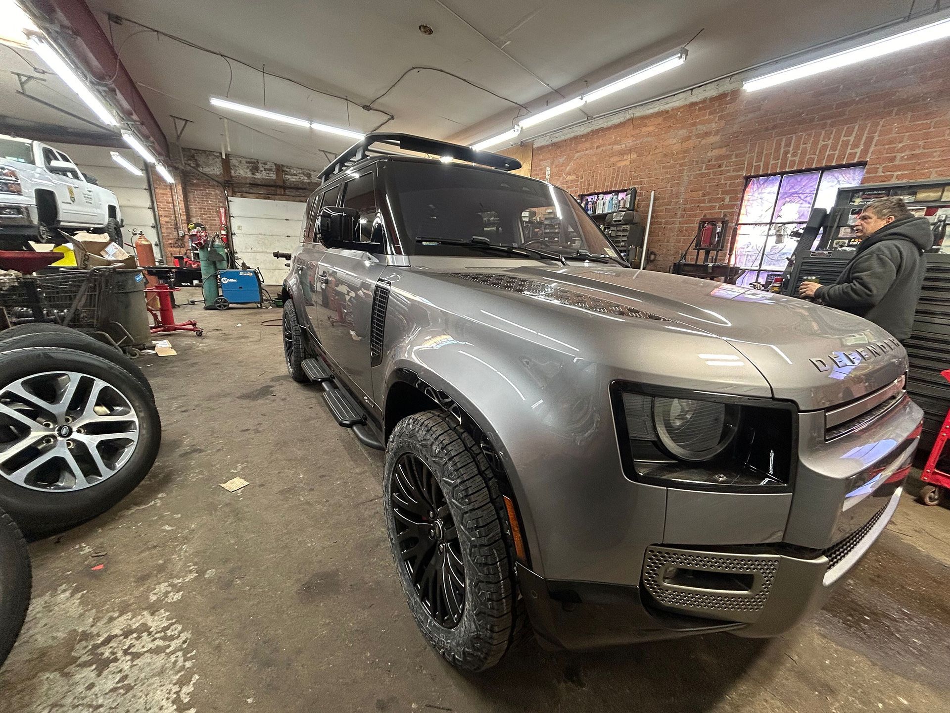 A gray Land Rover Defender - front and side view