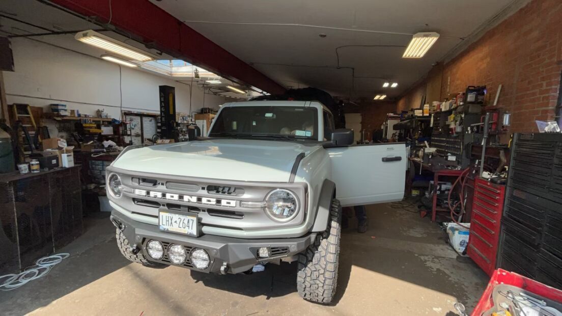 A white truck is parked in a garage with its doors open