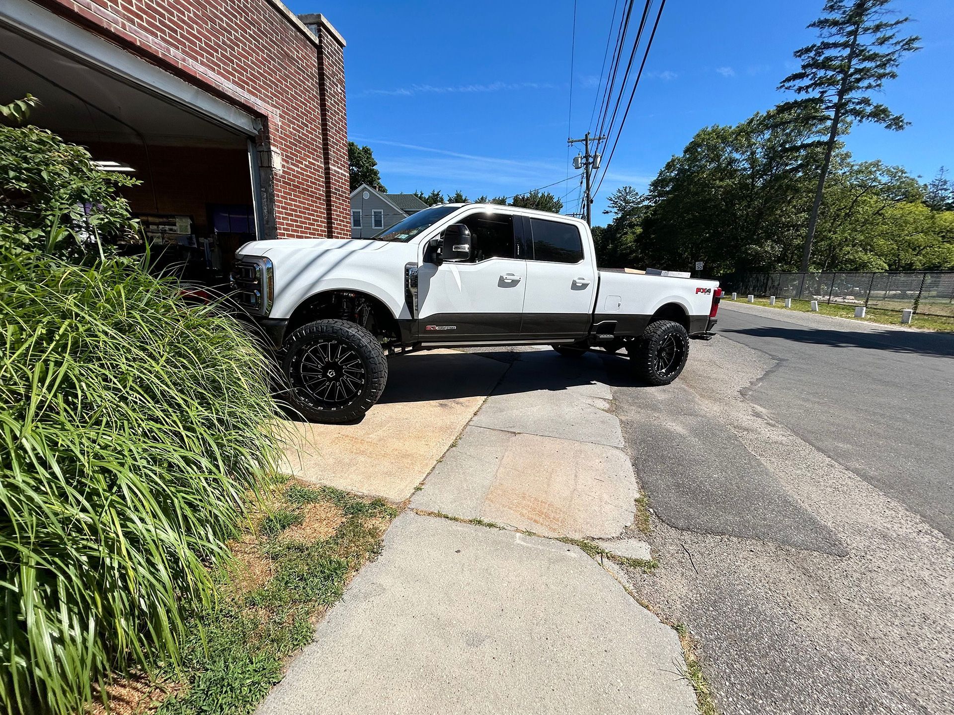 A white truck is parked on the side of the road next to a sidewalk