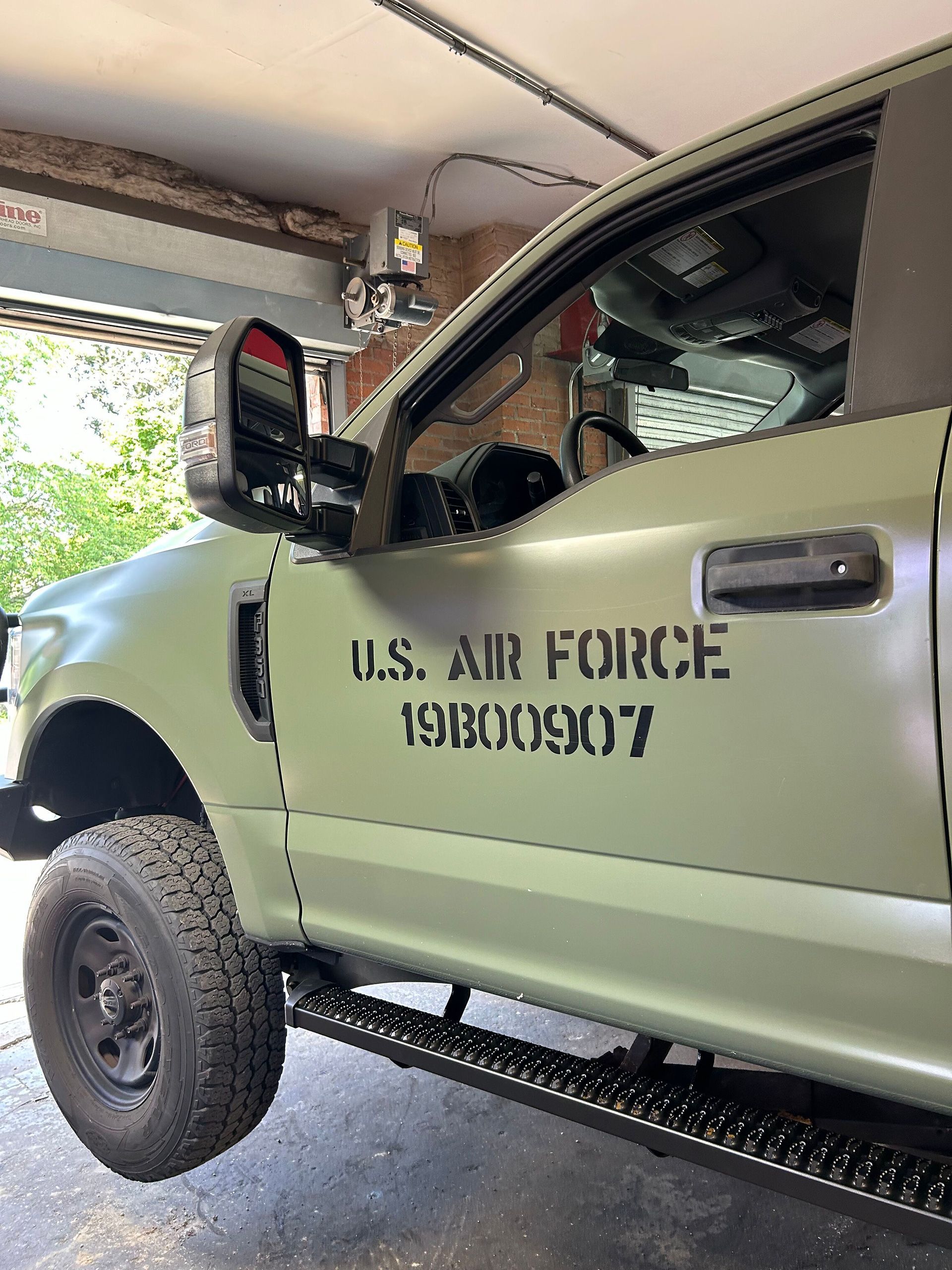 A green-painted truck is parked in a garage