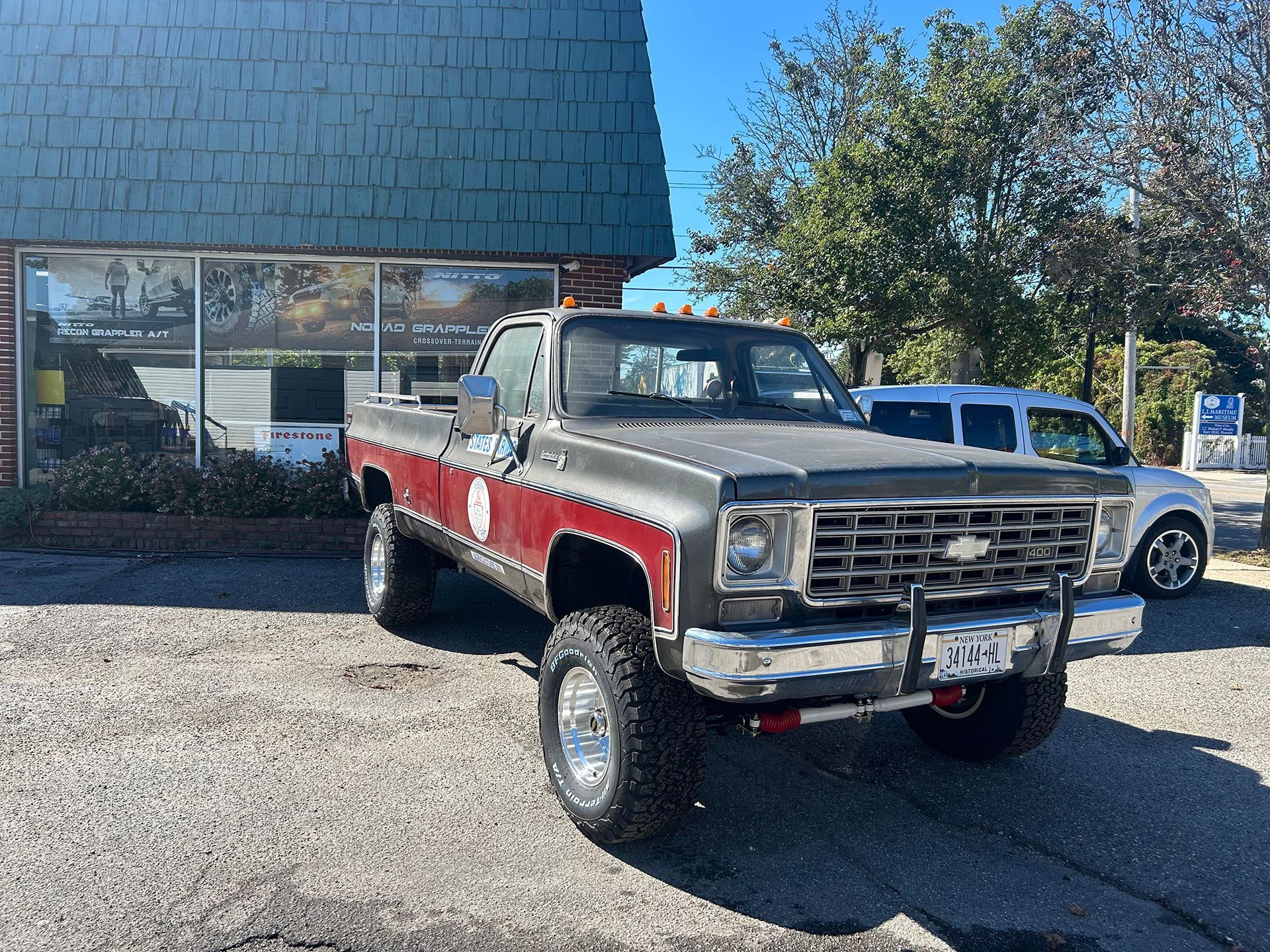 A red and gray truck is parked in front of a building