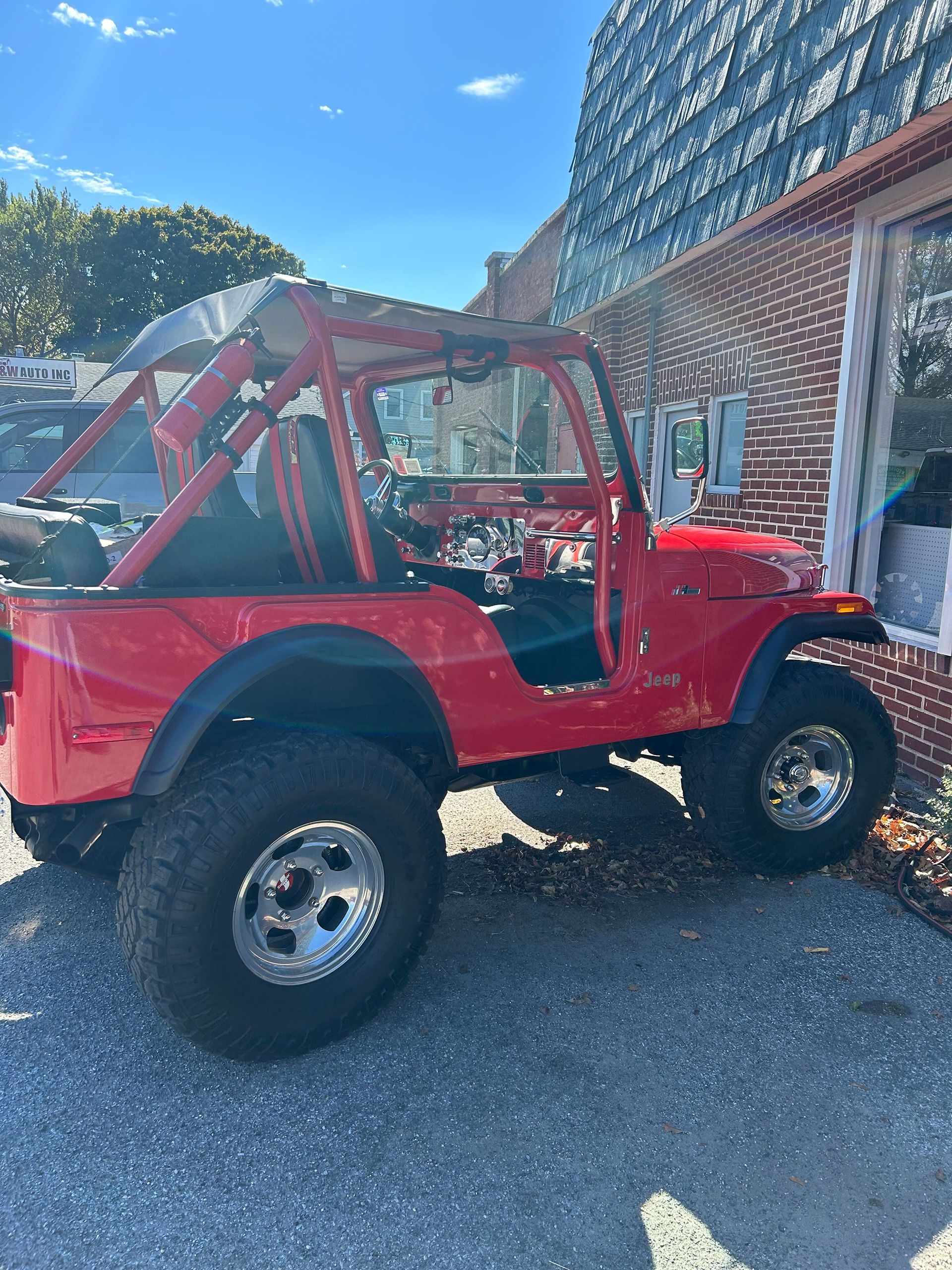 A red Jeep is parked in front of a brick building