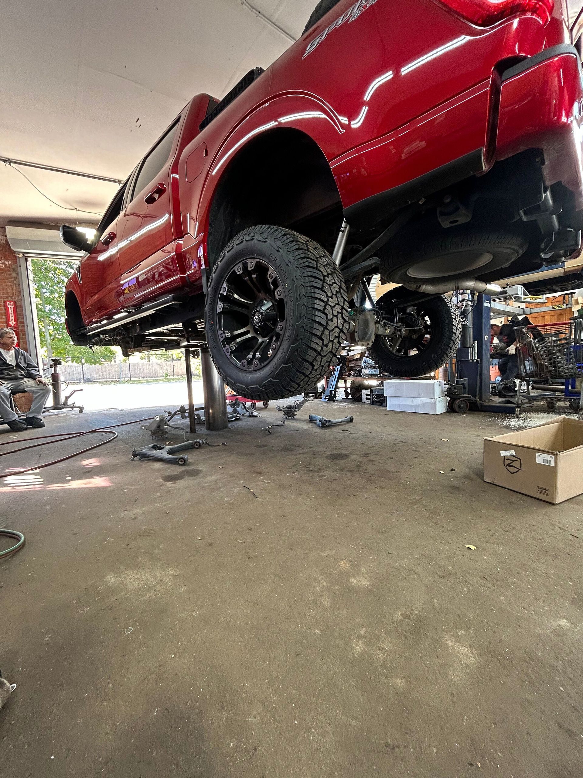 A red truck is sitting on a lift in a garage