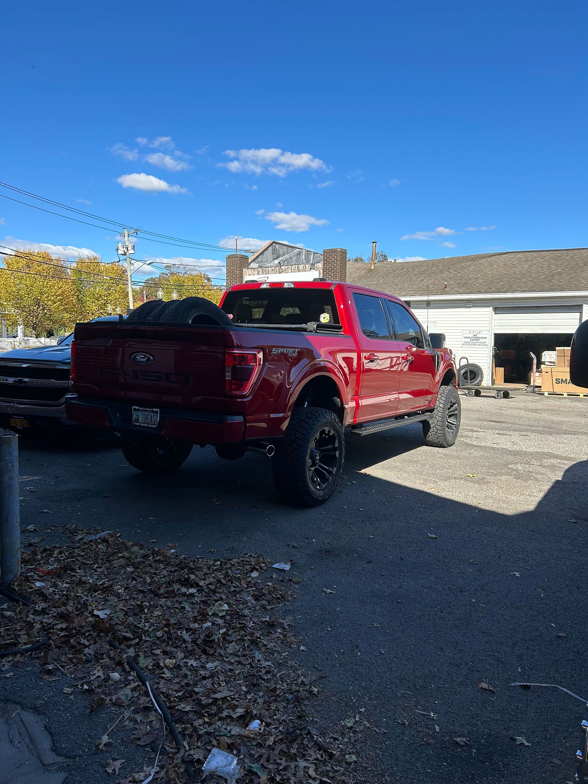 A red truck is parked in a parking lot in front of a building