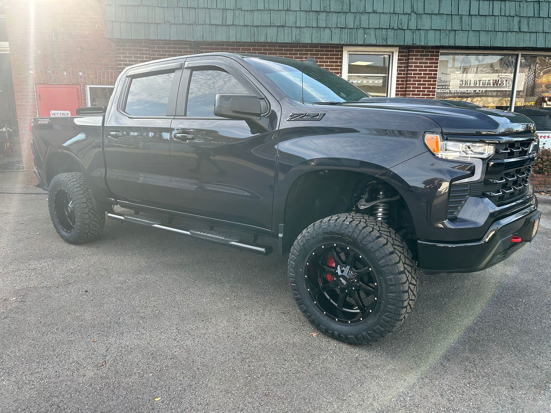 A black truck is parked in front of a brick building