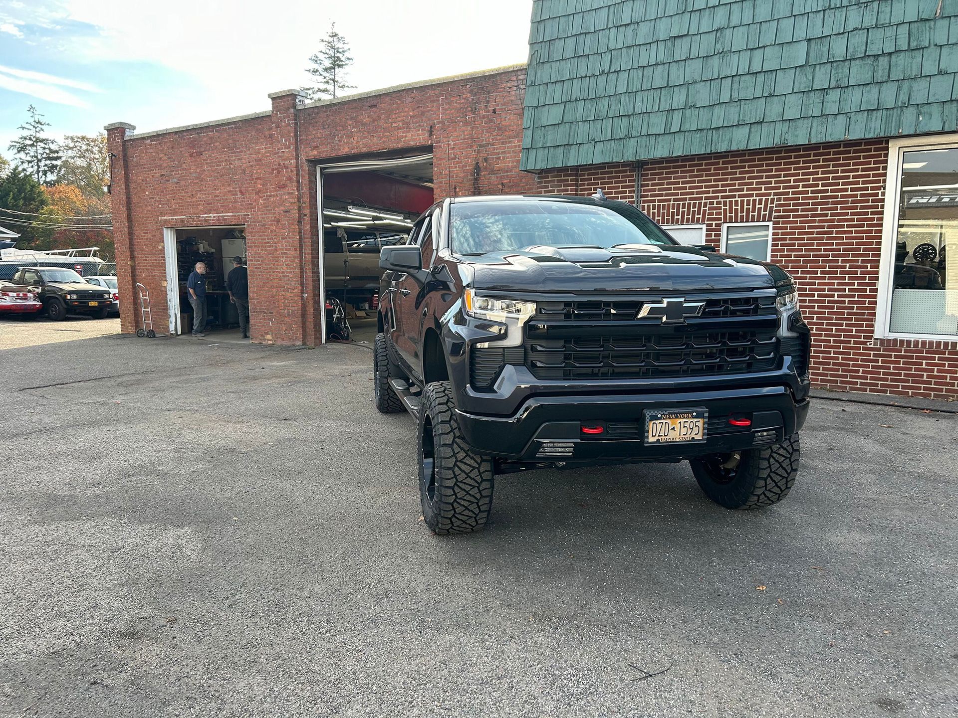 A black truck is parked in front of a truck customization shop