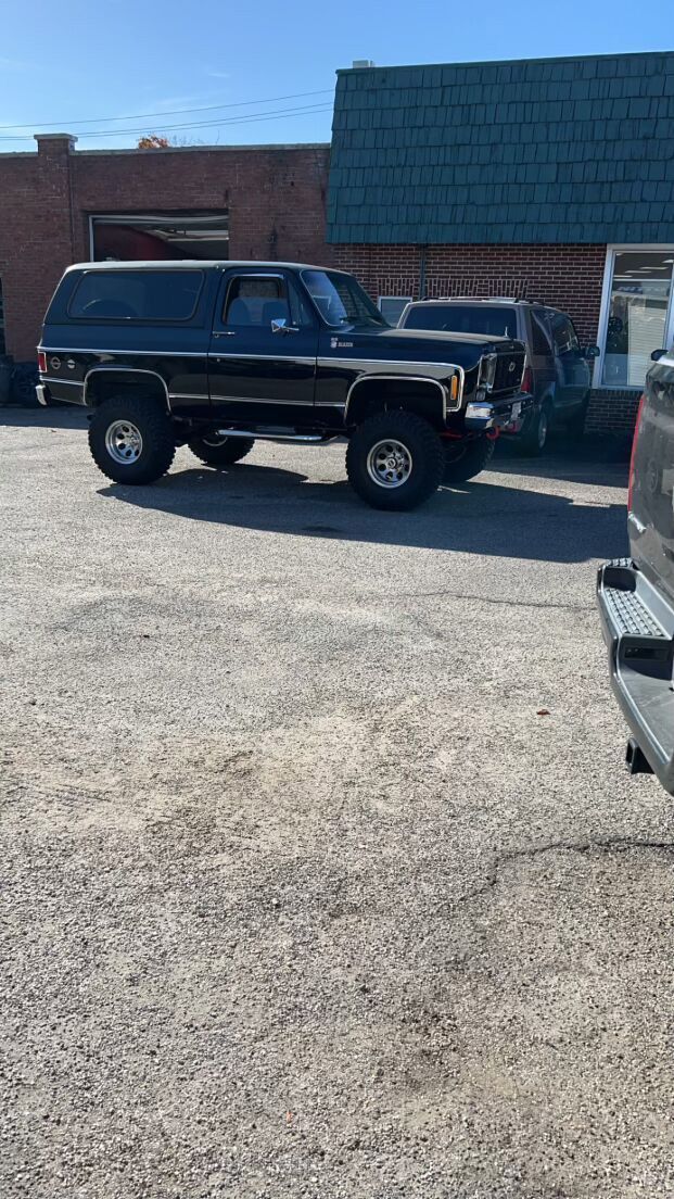 A black Jeep is parked in a parking lot in front of a building